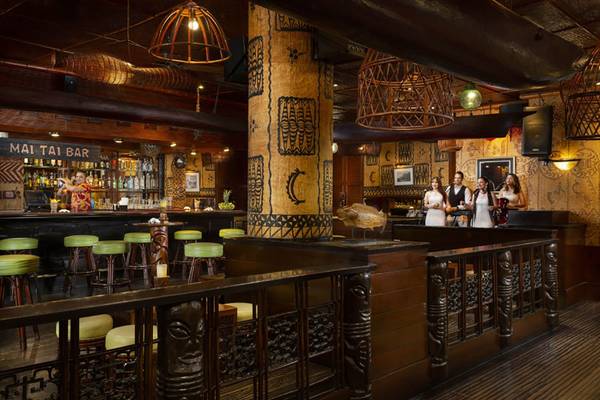 Innenansicht der Bar im Beach Rotana Hotel mit grünen Stühlen und einer Gruppe von Leuten am Tresen.