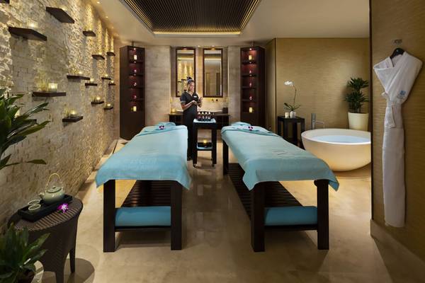 Spa-Behandlungsraum im Beach Rotana Hotel mit zwei Massageliegen und einem großen Badewanne.