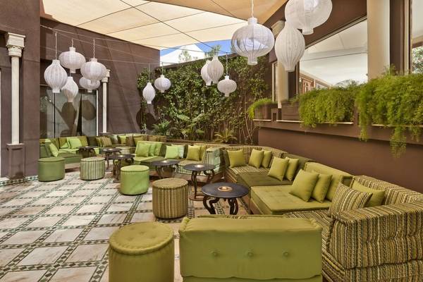 Lounge-Bereich im Palmeraie Palace Hotel mit grünen Sofas, Tischen und dekorativen Lampen.