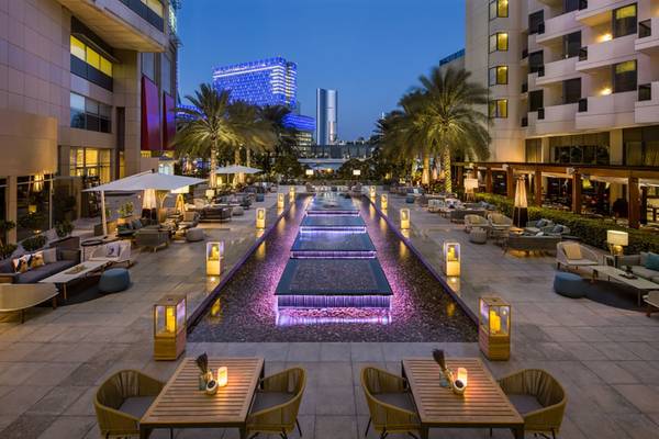 Außenbereich des Beach Rotana Hotels bei Nacht mit Wasserbrunnen und Möbeln.