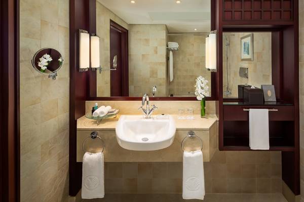 Badezimmer im Beach Rotana Hotel mit Spiegel, Waschbecken und Handtüchern.
