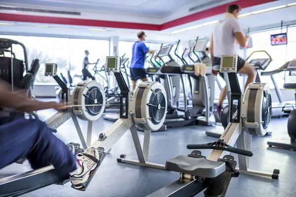 Fitnessstudio mit Rudergeräten und Laufbändern, mehrere Personen trainieren