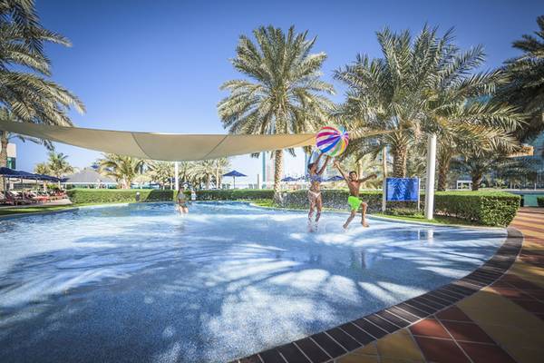 Zwei Personen spielen mit einem Ball im Pool des Beach Rotana.