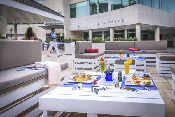 Außensitzbereich im Beach Rotana Hotel mit Tischen, Cocktails und Essen.