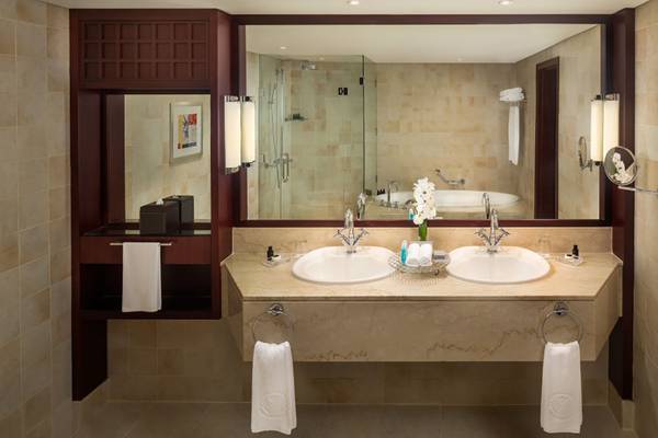 Badezimmer im Beach Rotana Hotel mit Doppelwaschbecken und Badewanne im Hintergrund.