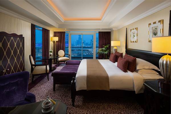 Schlafzimmer im Beach Rotana Hotel mit großem Bett, Nachttischen und Stadtblick.