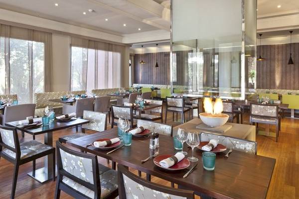 Restaurantbereich im Palmeraie Palace mit gedeckten Tischen, Feuerschüssel und Panoramafenstern.