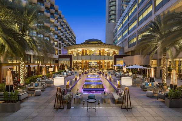 Außenbereich des Beach Rotana Hotels mit Wasserfall, Palmen und Loungemöbeln bei Nacht