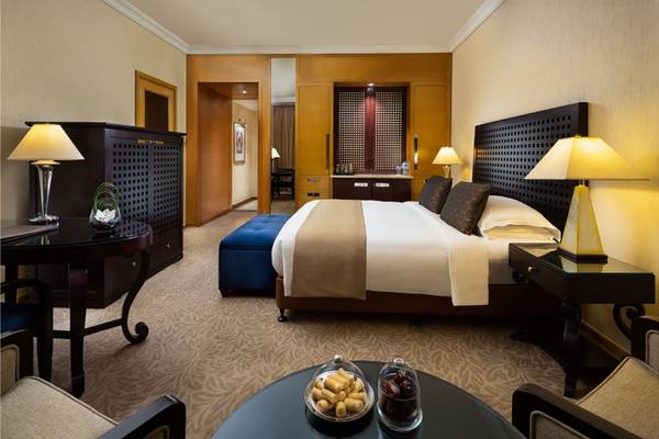 Das elegante Schlafzimmer im Beach Rotana Hotel mit einem großen Bett, Nachttischen und Lampen.