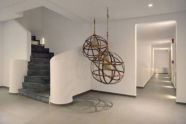 Innenbereich des Myconian Korali Relais & Chateaux mit einer Treppe und zwei hängenden Metalllampen.