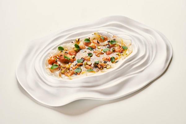 Gerichteteller Teller mit Fisch und Pistazien in weißer Schüssel