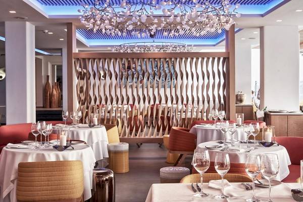 Innenansicht des Restaurants im Myconian Korali Relais & Chateaux mit eleganten Tischen, Stühlen und Kerzen.