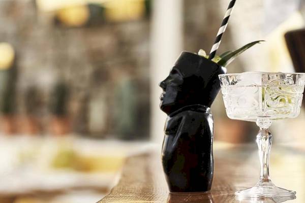 Ein schwarzer Cocktail-Shaker und ein Glas auf einem Holztisch im Myconian Korali Hotel.