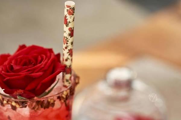 Ein roter Cocktail in einem Glas mit einer roten Rose auf einem Strohhalm