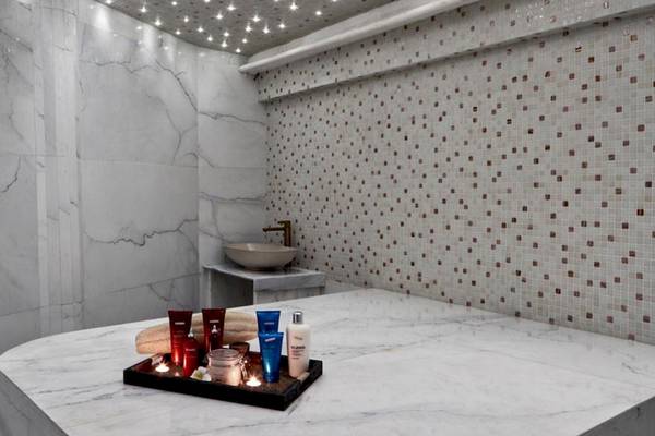 Spa-Raum im Myconian Korali Relais & Chateaux Hotel mit Marmorwänden und Tisch für Körperpflegeprodukte.