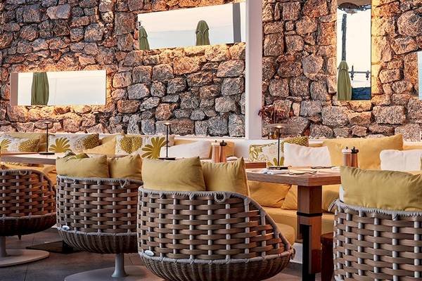 Innenansicht des Restaurants im Hotel Myconian Korali Relais & Chateaux mit Steinwänden und Meerblick.