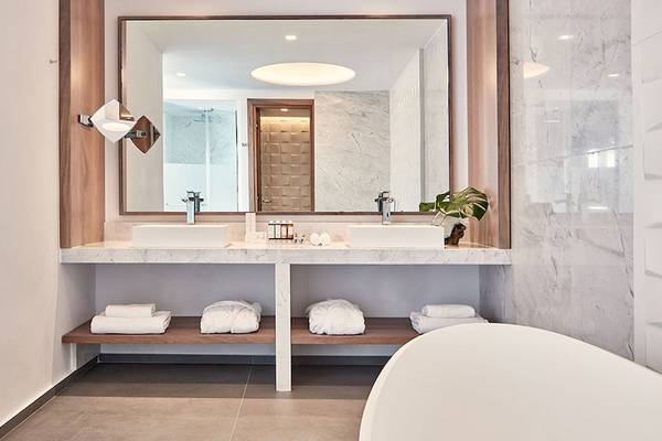 Das Badezimmer des Myconian Korali Relais & Chateaux mit zwei Waschbecken, Spiegel und Badewanne.