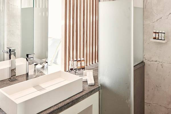 Hotelbadezimmer von Myconian Korali Relais & Chateaux mit modernem Design und Marmorwänden.