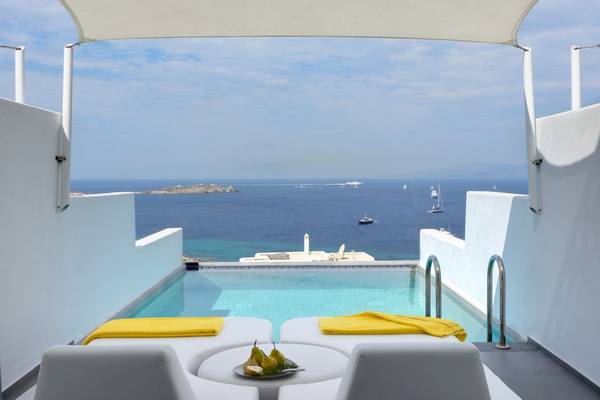Terrasse mit Meerblick im Myconian Korali Relais & Chateaux mit gelben Handtüchern und einer Schale mit Früchten.