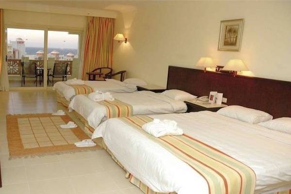 Hotelzimmer im Serenity Alpha Beach mit drei Betten, Fernseher, und Balkonzugang.