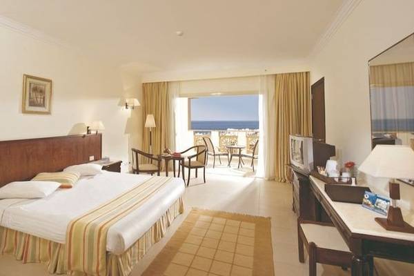 Hotelzimmer im Serenity Alpha Beach mit Blick auf den Ozean, Doppelbett, Balkon mit Möbeln und Fernseher.