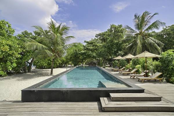 Außenpool des Barefoot Eco Hotels auf dem Strand mit Lounge-Stühlen und Sonnenschirmen.