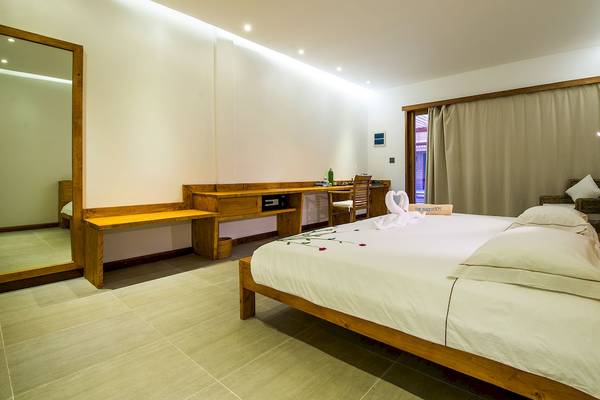 Das Schlafzimmer im Barefoot Eco Hotel mit einem großen Bett, weißen Laken, Kissen und einem Holzbettrahmen.