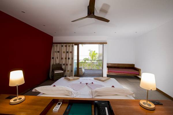 Schlafzimmer im The Barefoot Eco Hotel mit rotem Wand, weißem Bett, Deckenventilator, Lampen und Schreibtisch.