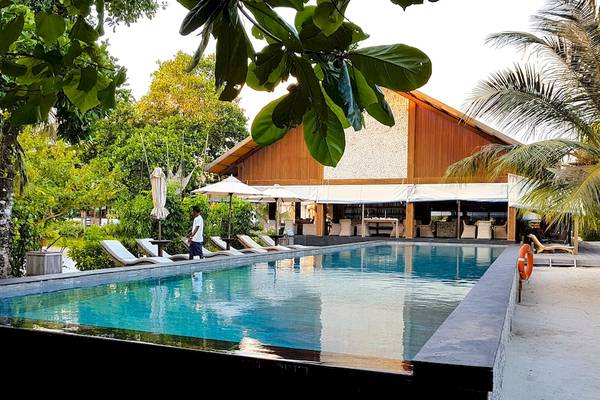 Außenbereich des Barefoot Eco Hotels mit Swimmingpool und Sonnenliegen.