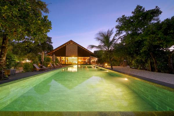 Pool im Barefoot Eco Hotel bei Nacht mit Lounge-Sesseln und Bäumen.