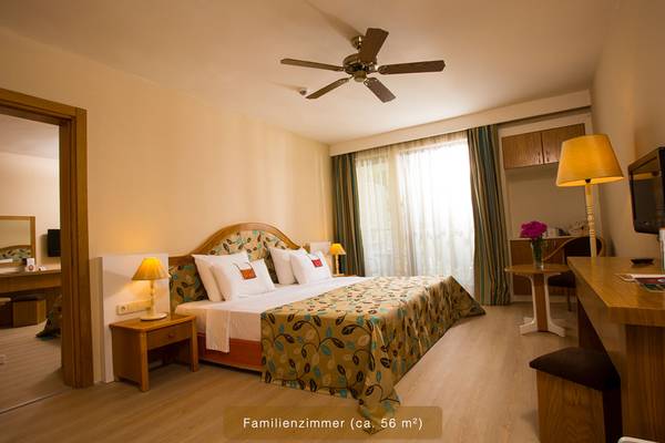 Familienzimmer im Defne Star Hotel mit Doppelbett, Lampen, Schreibtisch und Fernseher.