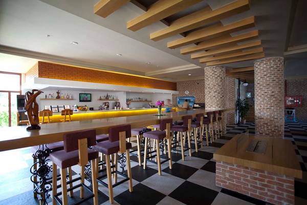 Innenansicht der Bar im Defne Star Hotel mit langen Holztischen und Barhockern.