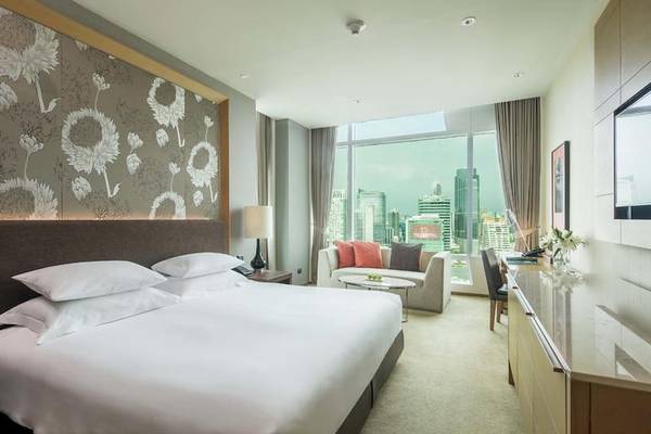 Zimmer im Eastin Grand Hotel Sathorn mit einem Bett, Sofa, Schreibtisch und Stadtblick.