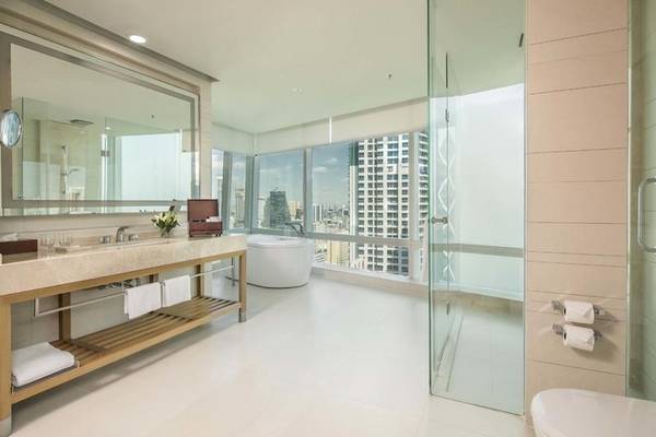 Badezimmer im Eastin Grand Hotel Sathorn mit Badewanne, Waschtisch und Stadtblick.