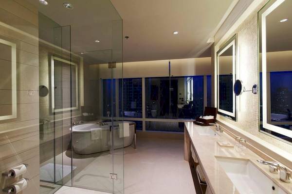 Badezimmer im Eastin Grand Hotel Sathorn mit Badewanne, Glasdusche und Waschbecken.