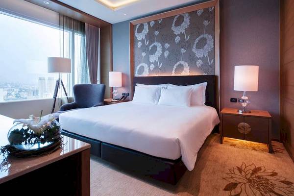 Schlafzimmer im Eastin Grand Hotel Sathorn mit großem Bett, Nachttischen und Stadtblick.