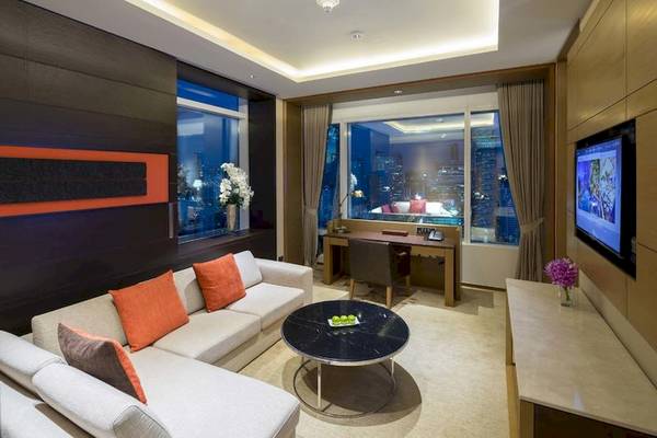 Wohnbereich im Eastin Grand Hotel Sathorn mit Couch, Tisch und Fernseher.