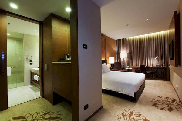 Innenansicht eines Schlafzimmers im Eastin Grand Hotel Sathorn mit einem Bett, Schreibtisch und Bad.