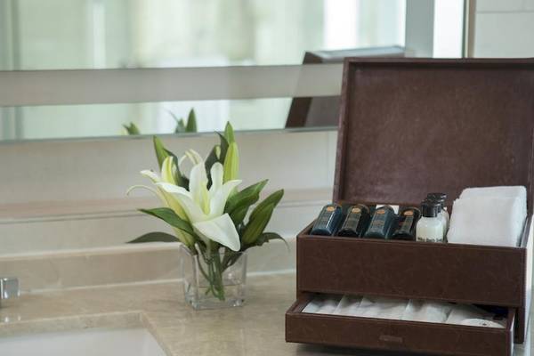 Badezimmer-Anrichte im Eastin Grand Hotel Sathorn mit Blumen, Pflegeprodukten und Handtüchern