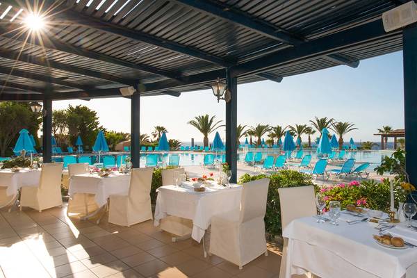 Außenbereich des Iberostar Creta Panorama & Mare Hotels mit einem Pool und gepolsterten Stühlen.