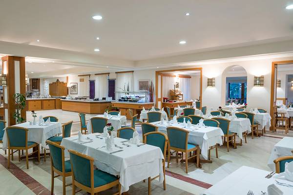 Innenansicht des Restaurants im Iberostar Creta Panorama & Mare Hotel mit gedeckten Tischen und Stühlen.