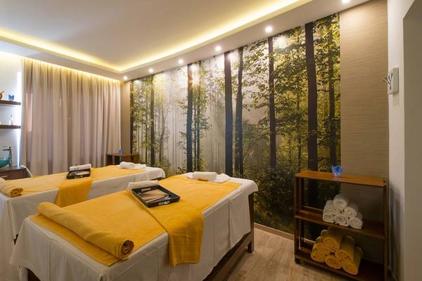 Spa-Behandlungsraum im Iberostar Creta Panorama & Mare Hotel mit zwei Massagetischen und einem großen Wandbild von Bäumen.