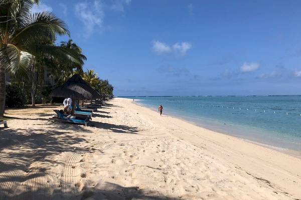 Strand des JW Marriott Mauritius Resorts mit weißen Sand, Palmen und Sonnenliegen.