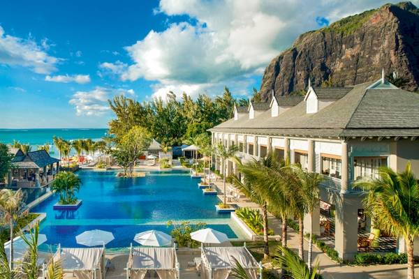 Außenbereich des JW Marriott Mauritius Resorts mit Pool und Blick auf das Meer und einen Berg.