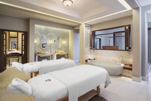 Spa-Behandlungsraum im JW Marriott Mauritius Resort mit zwei Massageliegen und Badewanne.