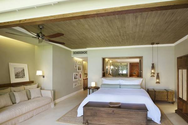 Schlafzimmer im JW Marriott Mauritius Resort mit großem Bett, Sofa, Deckenventilator und Holzmöbeln.