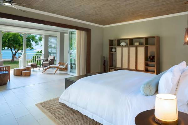 Schlafzimmer im JW Marriott Mauritius Resort mit Blick auf den Ozean und Holzmöbeln.