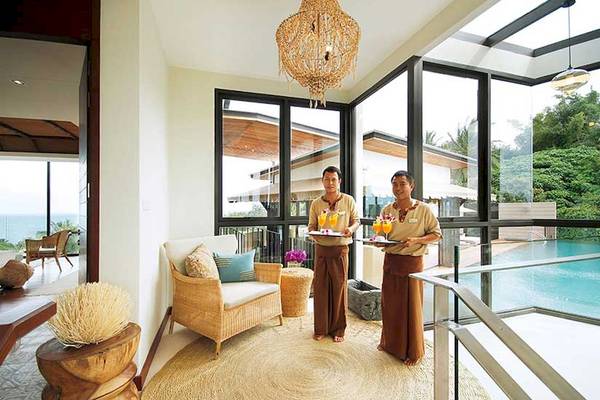 Zwei Mitarbeiter des Cape Panwa Hotels servieren Cocktails auf der Terrasse.