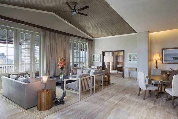 Wohnbereich im JW Marriott Mauritius Resort mit Holzboden, Sofas, Esstisch und Fenstern.