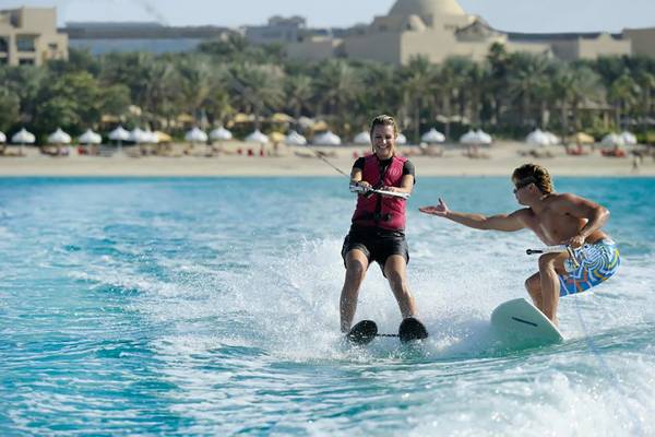 Zwei Leute machen Wasserski im Ozean vor dem The Palace At One & Only Royal Mirage Hotel.
